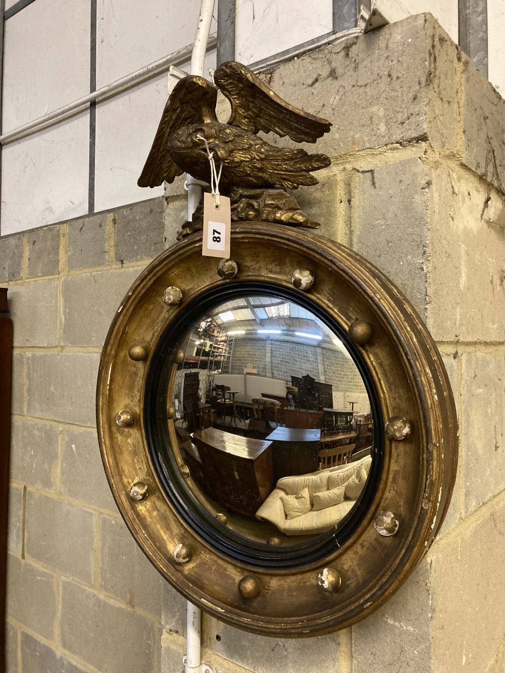 A Regency carved giltwood and gesso circular convex wall mirror with eagle pediment, height 69cm, width 50cm